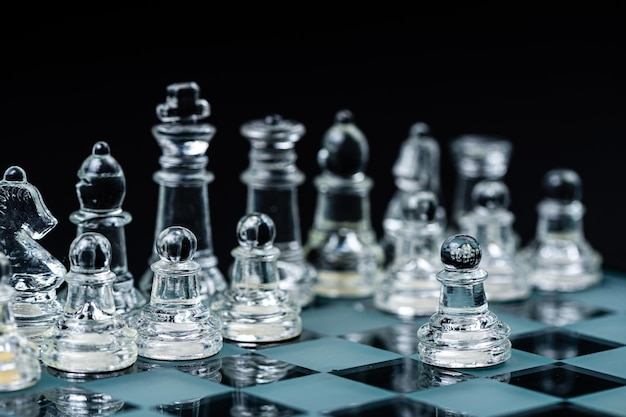 Peças de xadrez transparentes de vidro em um foco seletivo de tabuleiro de damas fechado isoladas em preto