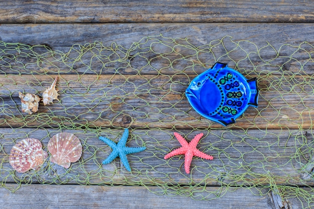 Peces, conchas, estrellas de mar en la red sobre un fondo de madera.