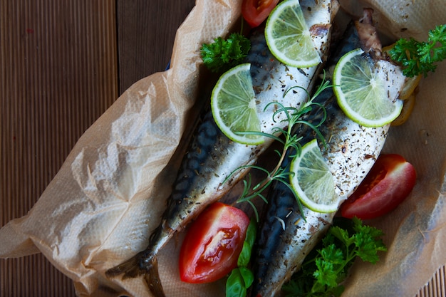 Peces de mar enteros al horno sobre papel de hornear con limón y hierbas.