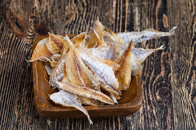 Peces pequeños secos y masacrados en una mesa de madera