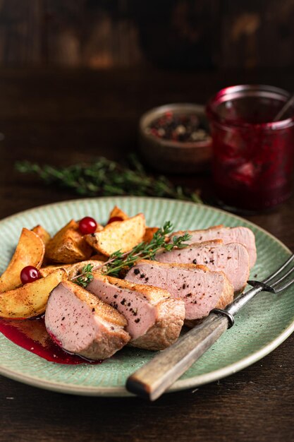 Pecho de pato con patatas y salsa de bayas en fondo de madera enfoque selectivo