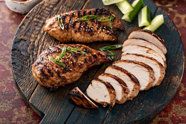 Pecho de pollo teriyaki a la parrilla en rodajas en una tabla con cebollas verdes