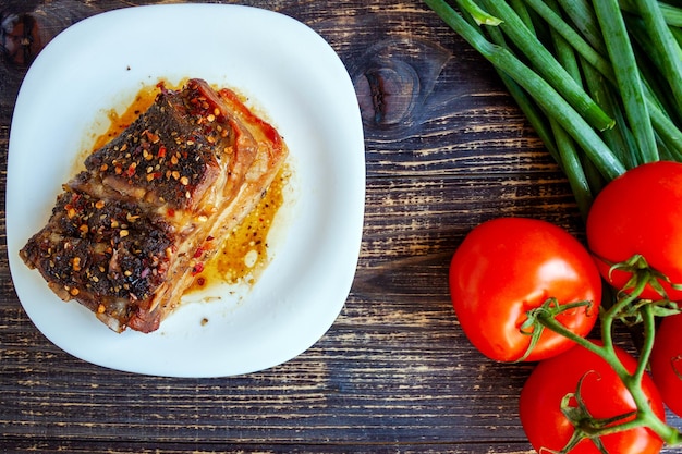 Pechuga frita picante con tomates frescos y plumas de cebolla verde sobre un fondo de madera oscura