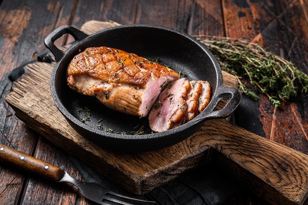 Pechuga de pato asada en una sartén, filete de carne de ave con hierbas. Fondo de madera. Vista superior.