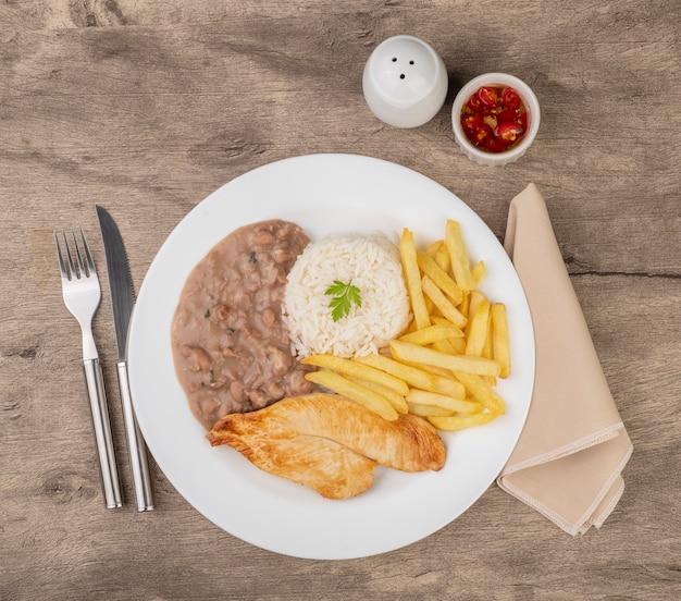 Pechuga de pollo, arroz, frijoles y papas fritas. Plato ejecutivo típico brasileño.