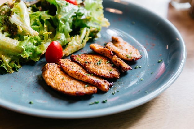 La pechuga de pollo asada a la parrilla Bbq con la ensalada sirvió en placa azul en la tabla de madera.