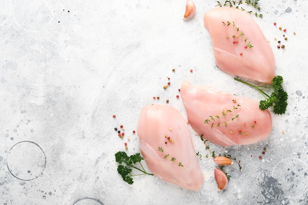 Foto pechuga de pollo filetes de pechuga de pollo cruda en placa de cerámica negra sobre tabla de cortar de madera con hierbas y especias sobre fondo de mesa gris antiguo vista superior con espacio de copia