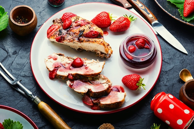 Pechuga de pollo en rodajas con salsa de fresas en el plato.Carne de pollo asada con fresas, dieta ceto.