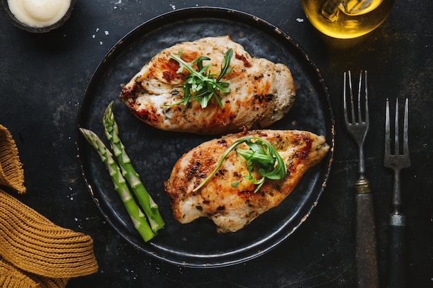 Pechuga de pollo sabrosa y apetitosa frita servida en una sartén con espárragos Fondo oscuro