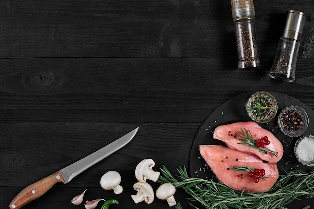 Pechuga de pollo en una tabla de cortar con hierbas y diferentes verduras sobre fondo de madera rústica Vista superior Espacio de copia Bodegón Plano