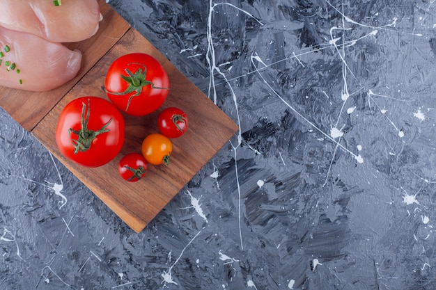 Pechuga de pollo y tomates en una placa, sobre fondo azul.