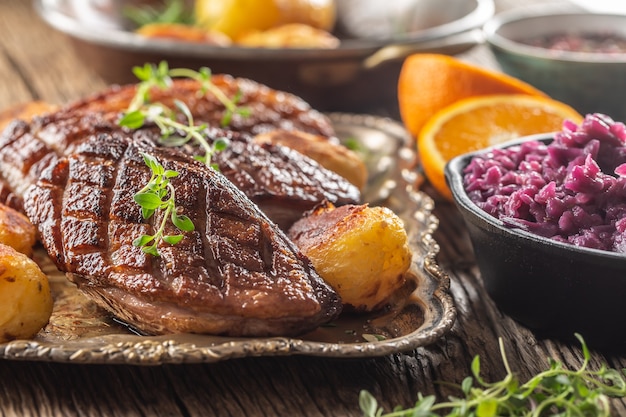 Pechugas de pato frescas a la plancha servidas con patatas asadas y col lombarda.