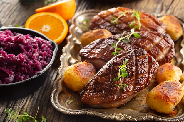 Pechugas de pato frescas a la plancha servidas con patatas asadas y col lombarda.