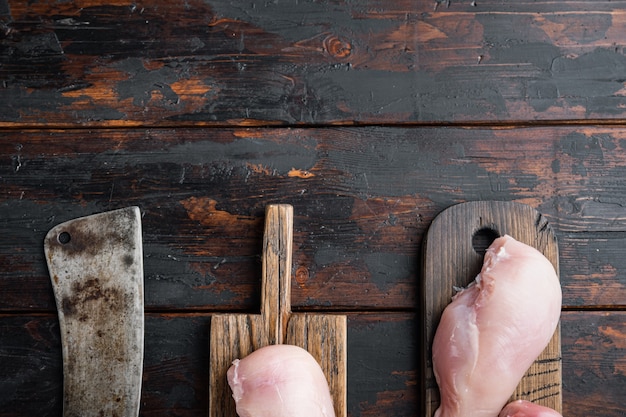 Pechugas de pollo con cuchillo de carnicero, sobre mesa de madera oscura, vista superior