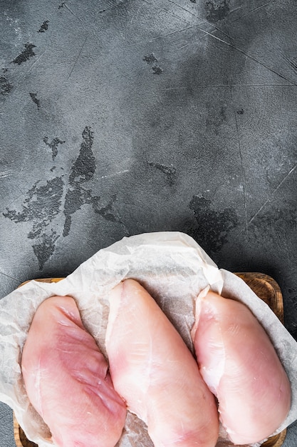 Foto pechugas de pollo sobre fondo gris, vista superior con espacio de copia