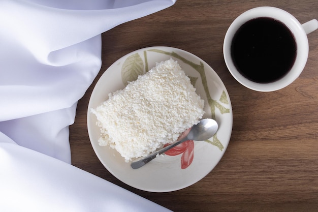 PEdaco de cuscuz em pires de porcelana sobre mesa de madeira prato tipico brasileiro feito com tapioca leite acucar e leite de coco Com copo de cafe and white towel