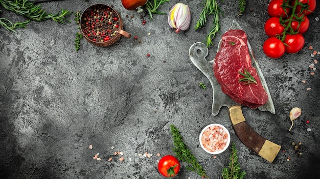 Pedaço de bife de alcatra cozido com especiarias servido no velho açougueiro de carne no fundo escuro de concreto com especiarias sal e pimenta. Formato de banner longo, vista superior.