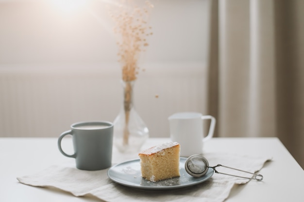 Pedaço de bolo caseiro fresco com xícara de cappuccino em uma mesa