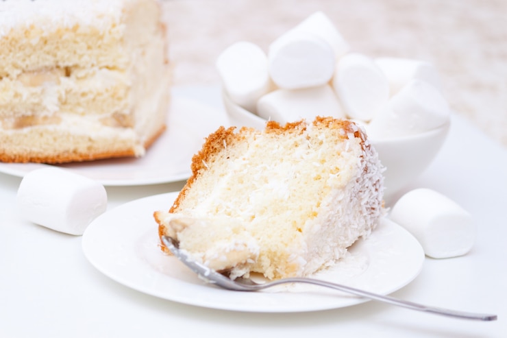 Foto pedaço de bolo com creme branco e lascas de coco e marshmallows
