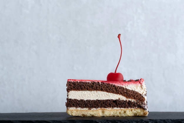 Pedaço de bolo de chocolate decorado com cereja. vista lateral para um pedaço de bolo. fundo branco.