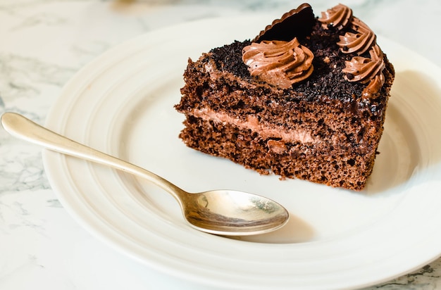 Pedaço de bolo de chocolate em um prato branco e uma xícara de ouro de café, closeup. Foco seletivo. Padrão sazonal e de feriados