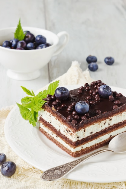 Pedaço de bolo de chocolate em um prato e uma xícara de mirtilos