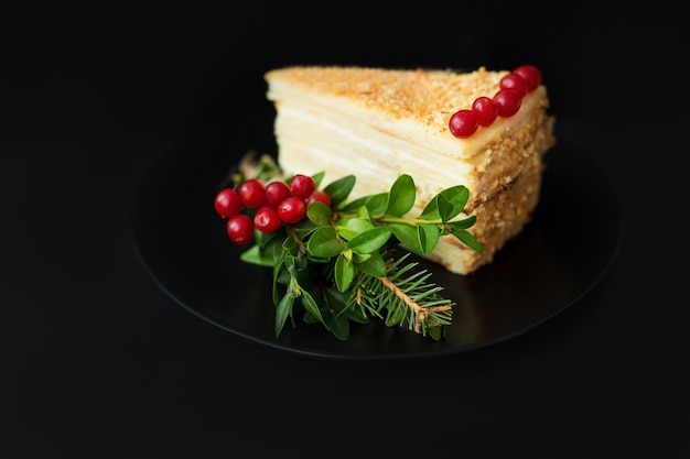 Pedaço de bolo decorado com árvore de Natal e frutas vermelhas em uma superfície preta