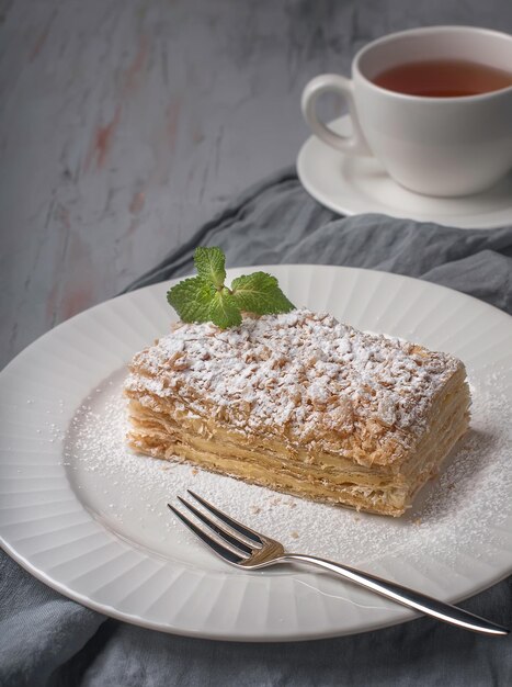 pedaço de bolo Napoleão com açúcar em pó no plano de fundo texturizado cinza