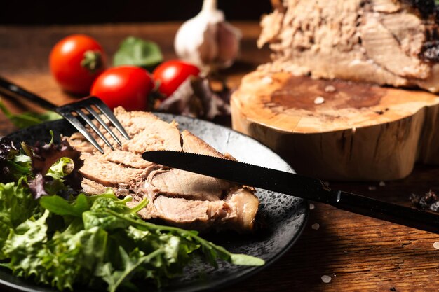 Pedaço de carne assado picado com salada verde de vegetais crus em um fundo de madeira