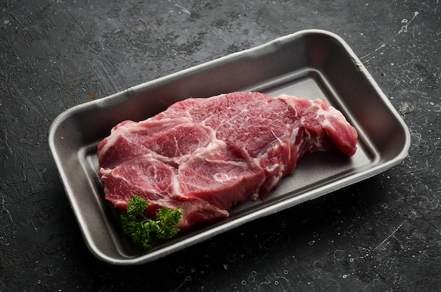 Pedaço de carne de porco fresca crua sobre fundo de pedra ardósia preta vista superior cozinhar