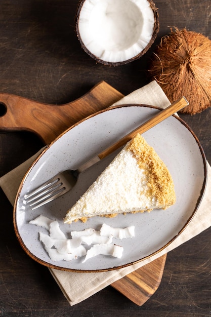 Pedaço de cheesecake de coco em um prato com coco fresco