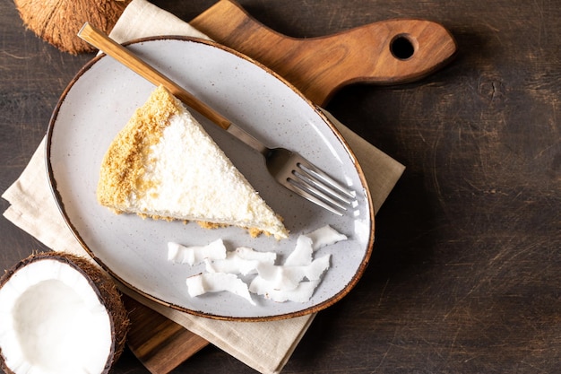 Pedaço de cheesecake de coco em um prato com coco fresco