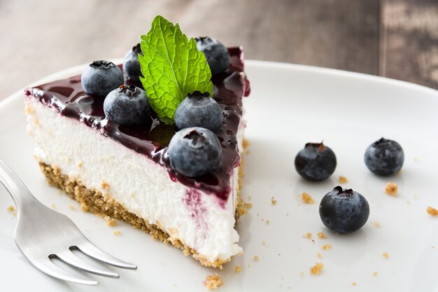 Pedaço de cheesecake de mirtilo na mesa de madeira