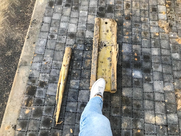 Pedaço de metal amarelo metálico e enferrujado está no asfalto garota de tênis branco caminha