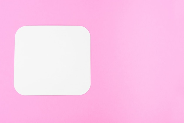 Pedaço de papel em branco sobre um fundo rosa, lugar para texto. Cartão em branco