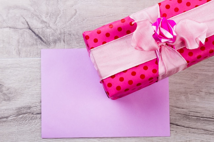 Foto pedaço de papel perto da caixa de presente. presente rosa e papel. use a imaginação para congtatulação. presente como atributo de festa de aniversário.