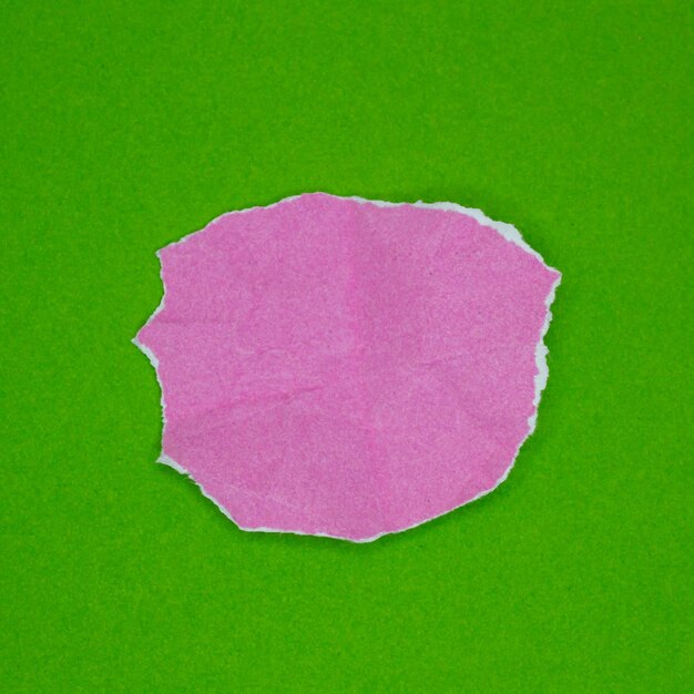 Pedaço de papel rasgado rosa isolado em fundo verde