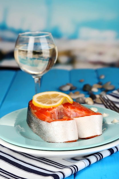 Pedaço de peixe vermelho no prato com especiarias e molho na mesa de madeira closeup