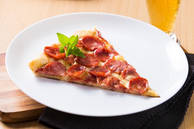 Foto pedaço de pizza de calabresa na mesa de madeira