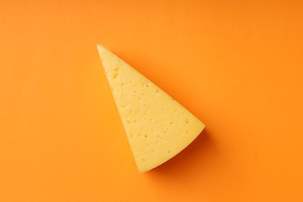 Pedaço de queijo duro em fundo laranja