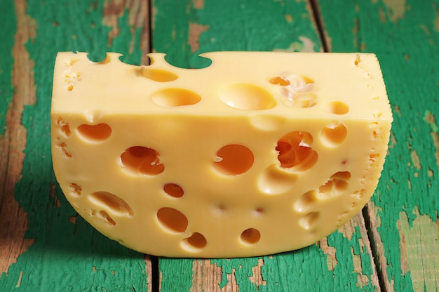 Pedaço de queijo em fundo verde de madeira