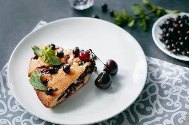 Pedaço de torta com mirtilos, rasberry, cerejas e hortelã para a sobremesa