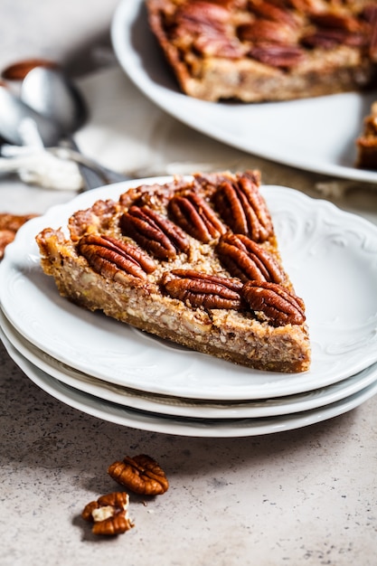 Pedaço de torta de noz-pecã em fundo cinza-marrom. Conceito de sobremesa vegan.