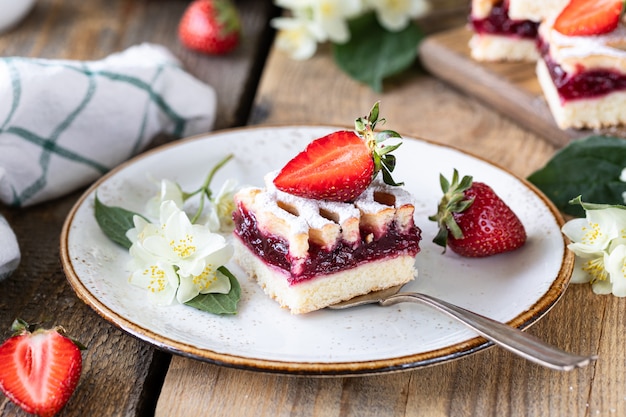 Pedaço de torta saborosa com morangos num prato branco na mesa de ooden.