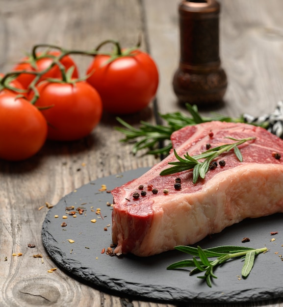 Pedaço fresco de carne bovina crua, bife striploin em uma superfície de madeira, vista de cima