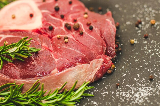 Pedaço fresco de carne grande bife no ossobuco ossobuco com um raminho de alecrim em um fundo preto