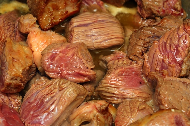 Pedaços crus de carne bovina fritos na panela