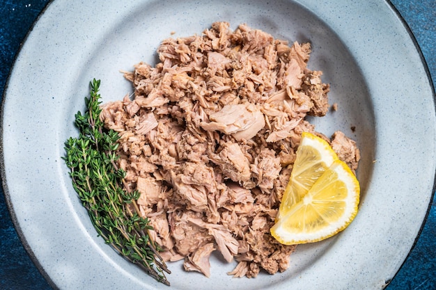 Foto pedaços de atum enlatados em azeite pronto para comer fundo azul vista superior