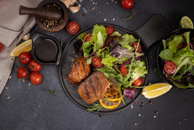 Pedaços de bife de atum orgânico grelhado em prato de cerâmica preta com salada em uma mesa