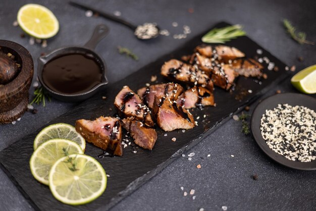 Pedaços de bife de atum orgânico grelhado em prato de pedra preta e molho de soja teriyaki